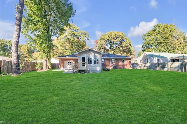 back of property with a fenced backyard and a yard
