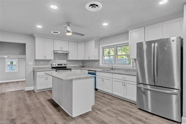 kitchen with decorative backsplash, white cabinetry, stainless steel appliances, and a sink