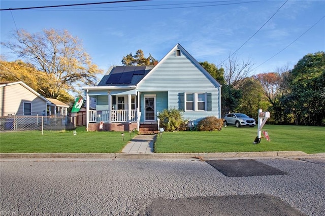 bungalow-style house with solar panels, a front yard, fence, and covered porch