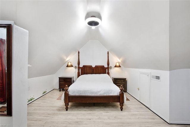 bedroom with vaulted ceiling, wood finished floors, and visible vents