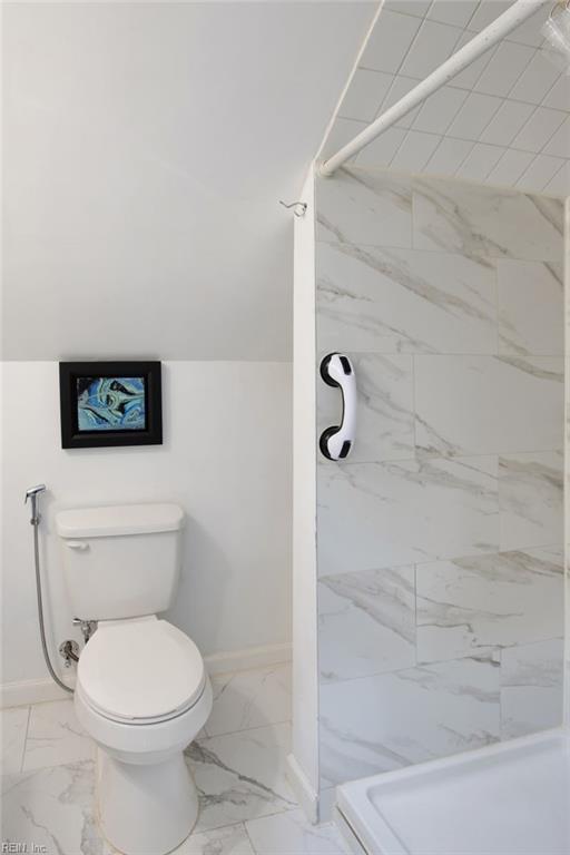 bathroom with baseboards, toilet, marble finish floor, and a shower stall