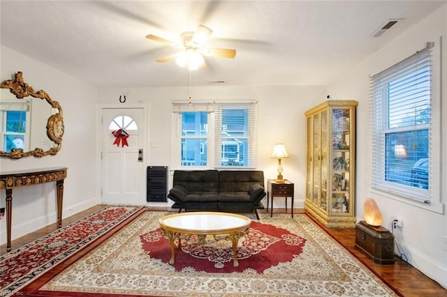 living room with visible vents, a ceiling fan, baseboards, and wood finished floors