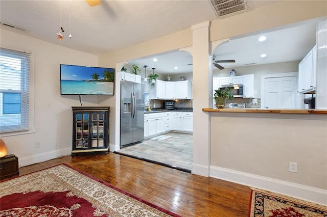 unfurnished living room featuring visible vents, baseboards, a ceiling fan, and wood finished floors