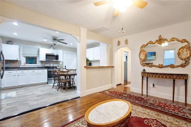 foyer with baseboards, recessed lighting, arched walkways, ceiling fan, and light wood-style floors