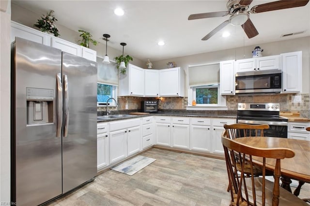 kitchen featuring backsplash, white cabinets, stainless steel appliances, and a sink