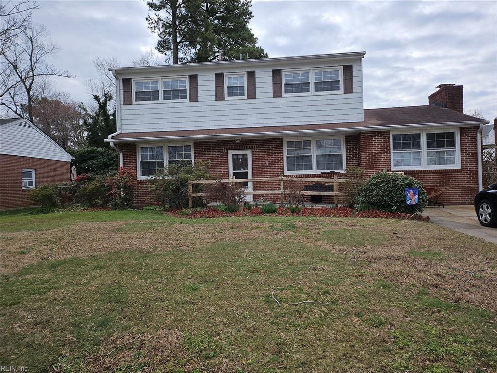 traditional-style house with brick siding, a chimney, and a front yard