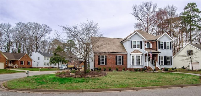 traditional-style house with brick siding, a residential view, driveway, and a front yard