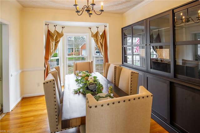 dining area featuring a notable chandelier, light wood-style floors, baseboards, and ornamental molding