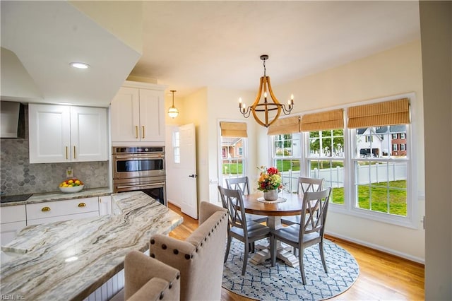 dining area featuring a notable chandelier, light wood-style floors, and baseboards