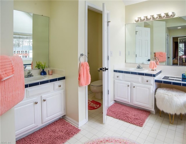 bathroom with toilet, two vanities, and a sink