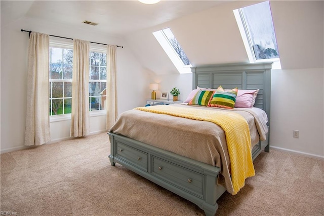 bedroom with lofted ceiling with skylight, visible vents, baseboards, and carpet