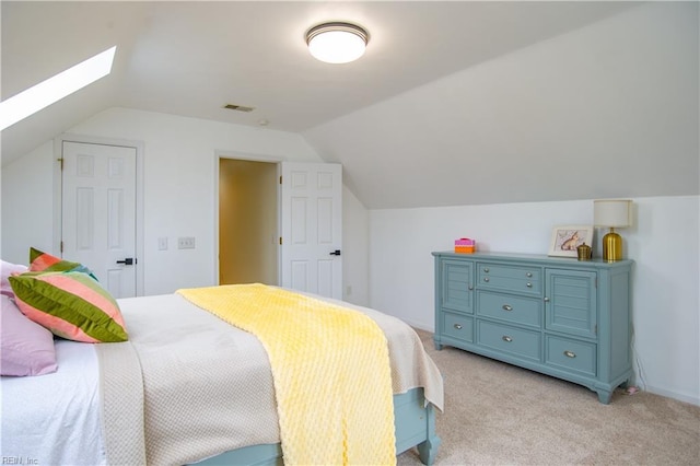 bedroom featuring visible vents, vaulted ceiling with skylight, and light colored carpet