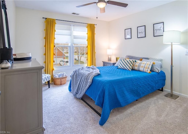 carpeted bedroom with visible vents, baseboards, and ceiling fan