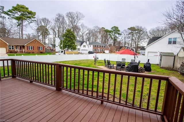 deck with a residential view, a lawn, a storage shed, a fenced backyard, and an outdoor structure