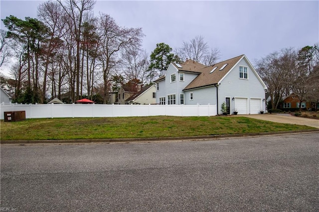 view of side of home with a yard, driveway, a garage, and fence