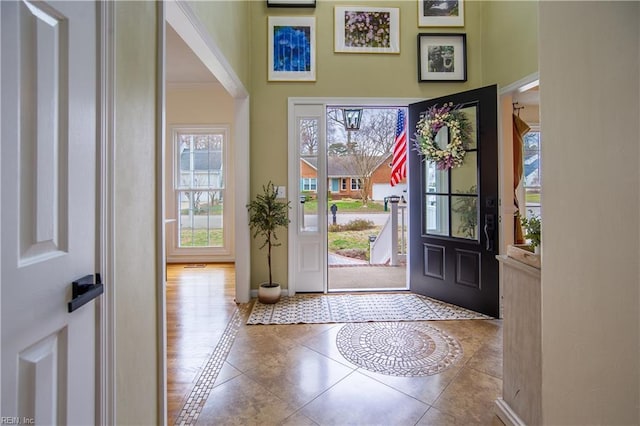 foyer featuring tile patterned floors, baseboards, and ornamental molding