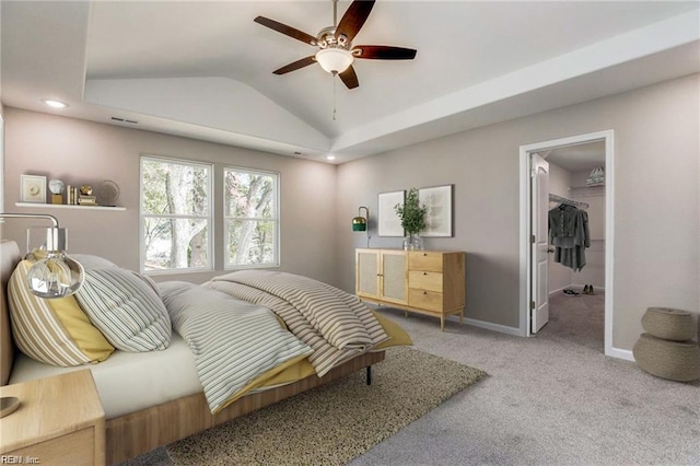 bedroom featuring visible vents, a walk in closet, baseboards, lofted ceiling, and carpet floors