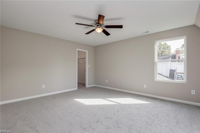 carpeted spare room with visible vents, baseboards, and a ceiling fan