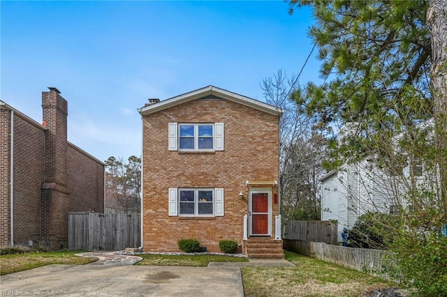 traditional-style house featuring entry steps, brick siding, and fence