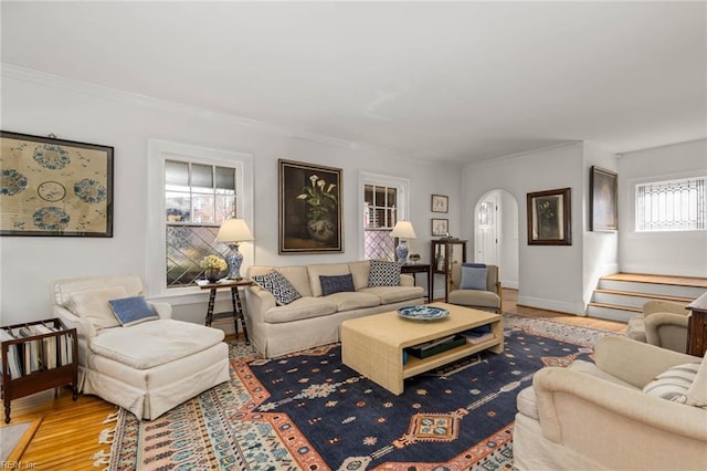 living room with crown molding, baseboards, stairs, wood finished floors, and arched walkways