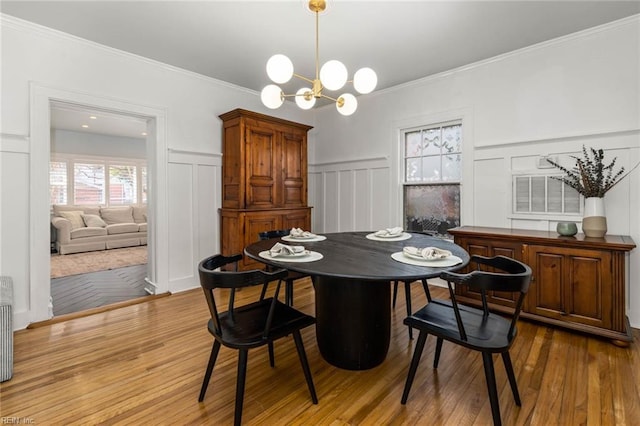 dining area with a notable chandelier, wood finished floors, and ornamental molding