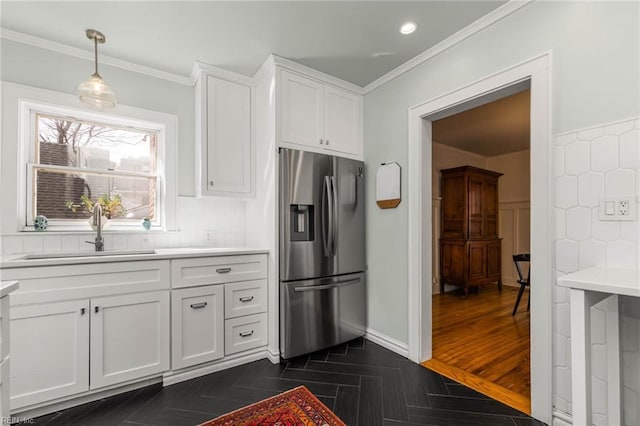 kitchen with stainless steel fridge with ice dispenser, ornamental molding, a sink, light countertops, and white cabinets