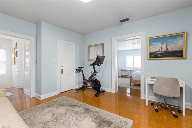 office area with visible vents, light wood-type flooring, and baseboards