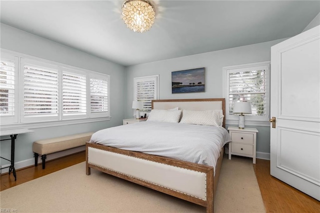 bedroom with baseboards, multiple windows, and wood finished floors