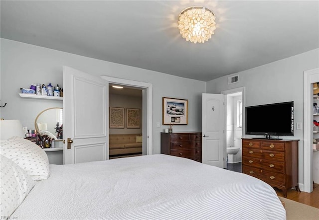 bedroom with visible vents, wood finished floors, and ensuite bathroom