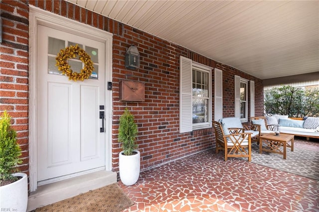 doorway to property with brick siding and covered porch