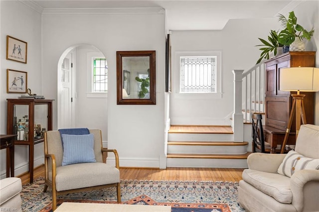 living area featuring stairway, plenty of natural light, ornamental molding, and wood finished floors