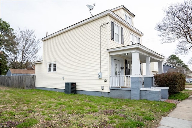 view of home's exterior featuring cooling unit, fence, covered porch, and a lawn