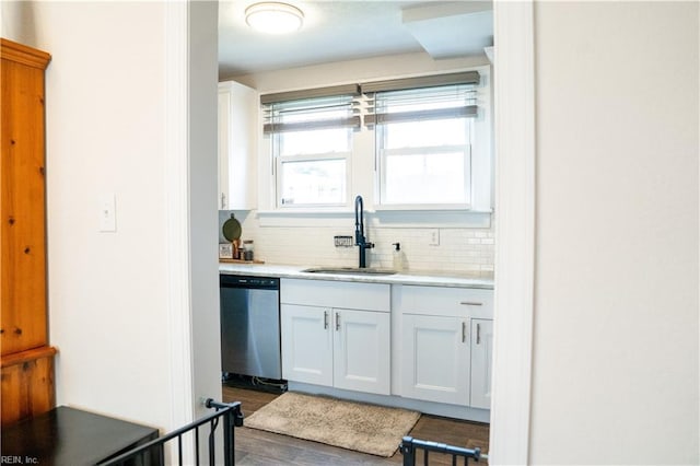 kitchen with tasteful backsplash, light countertops, stainless steel dishwasher, white cabinets, and a sink