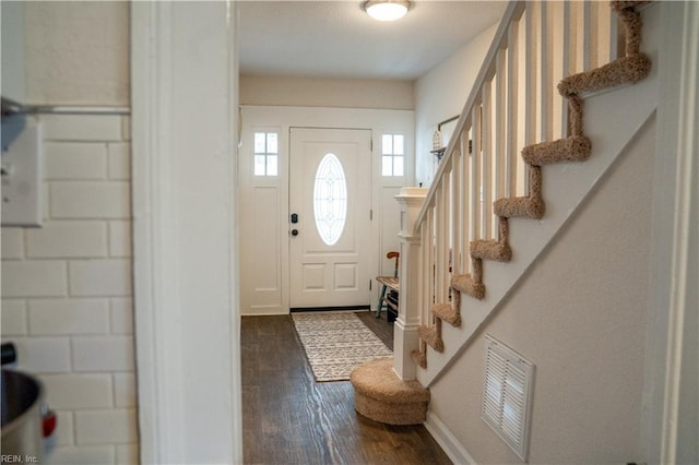 foyer with dark wood finished floors, visible vents, stairway, and baseboards