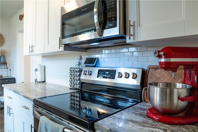 kitchen with decorative backsplash, white cabinets, light stone counters, and appliances with stainless steel finishes