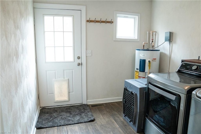 clothes washing area featuring electric water heater, wood finished floors, washing machine and dryer, baseboards, and laundry area