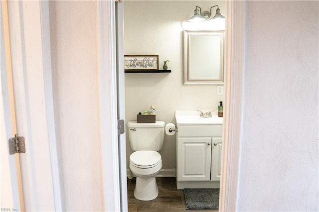 bathroom with toilet, vanity, and wood finished floors