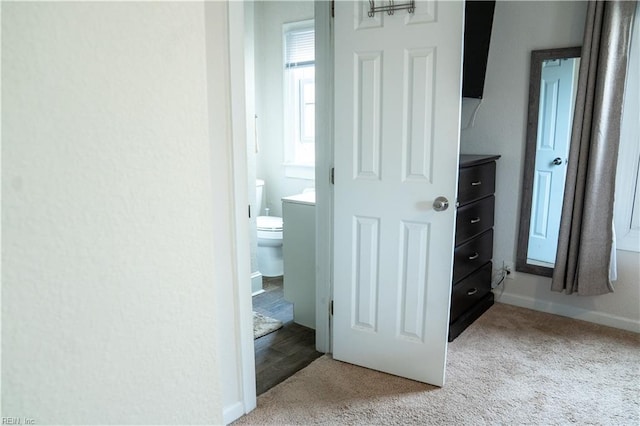 hall featuring light colored carpet and baseboards