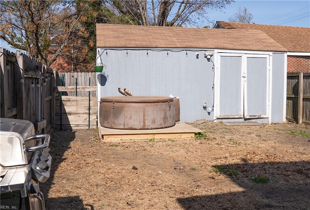 view of outbuilding featuring an outbuilding, a hot tub, and a fenced backyard