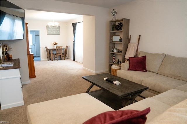 living area with light carpet, a notable chandelier, and baseboards