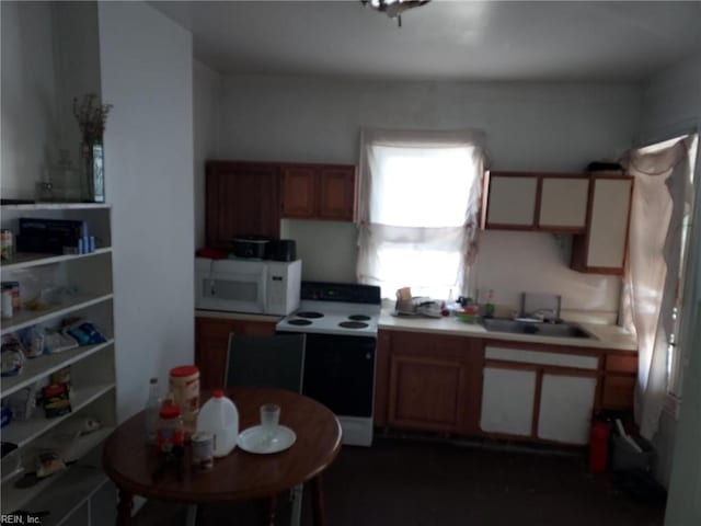 kitchen with brown cabinetry, white microwave, range with electric cooktop, a sink, and light countertops