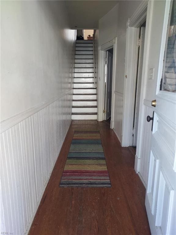 hall with stairs, wood finished floors, and a wainscoted wall