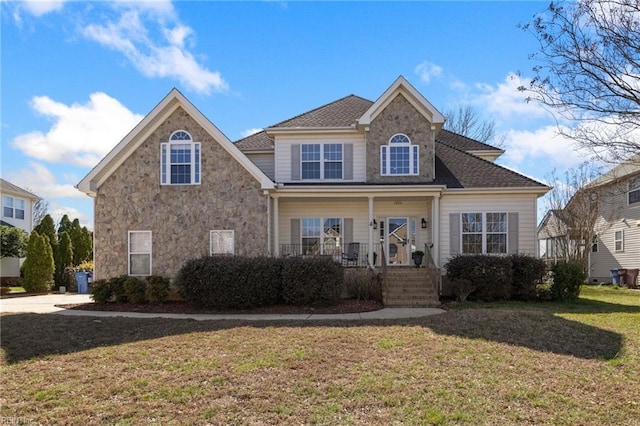 view of front of house featuring a front yard, a porch, stone siding, and a shingled roof