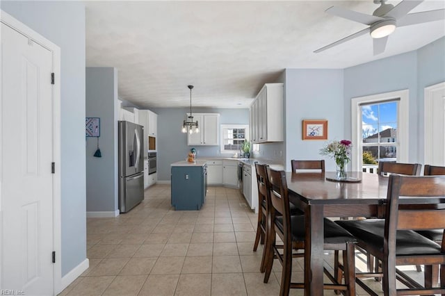 dining room with baseboards, light tile patterned flooring, and ceiling fan with notable chandelier