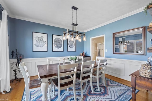 dining space with a notable chandelier, wood finished floors, and ornamental molding