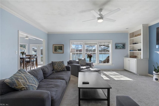 living room featuring carpet floors, ornamental molding, and a ceiling fan