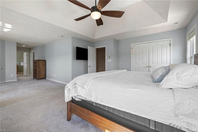 bedroom featuring a raised ceiling, baseboards, a closet, and light carpet