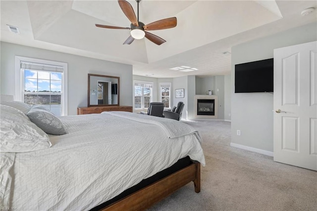 bedroom with a tray ceiling, carpet, visible vents, and baseboards