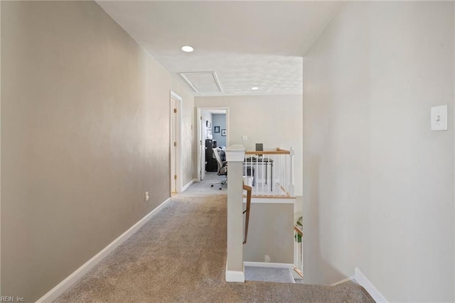 corridor featuring baseboards, an upstairs landing, and carpet