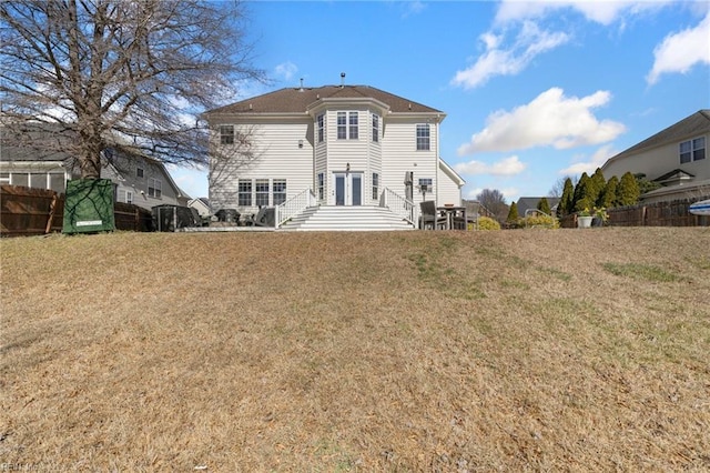 rear view of property featuring a lawn and fence